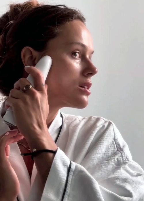 woman using handheld beauty device.